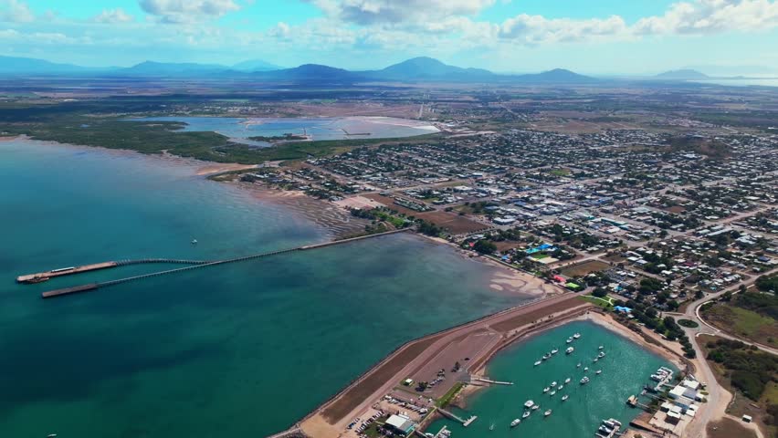 McCanes Bay Proserpine Bowen Jetty Coastal town Australia aerial drone landscape Horseshoe Bay Airlie Beach sunny blue sky marina boats cars harbor view Great Barrier Reef Whitsunday Region backwards
