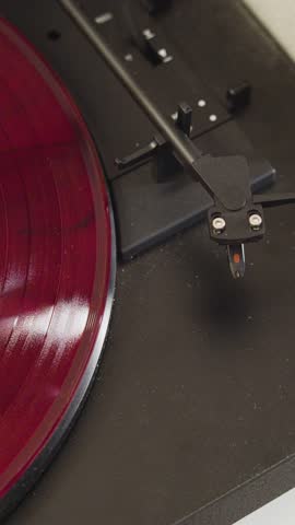 Close-up 4K footage of a red turntable disk vinyl record player. Vinyl record plays smoothly on a turntable in stunning vertical video.