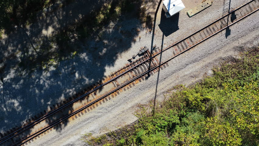 Top down aerial tracking along railroad tracks, abstract empty with forest tree shadows in Benton Arkansas
