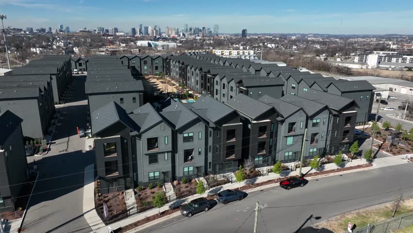 Aerial sunny view of modern luxury residential development in Nashville, Tennessee with contemporary apartment buildings, landscaped courtyards with pool and downtown skyline in back