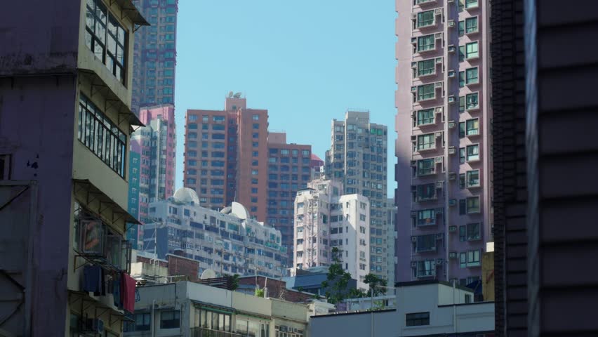 Panoramic view of apartment buildings and skyscrapers in downtown Hong Kong, China on a sunny day, showcasing dense urban living and modern architecture.