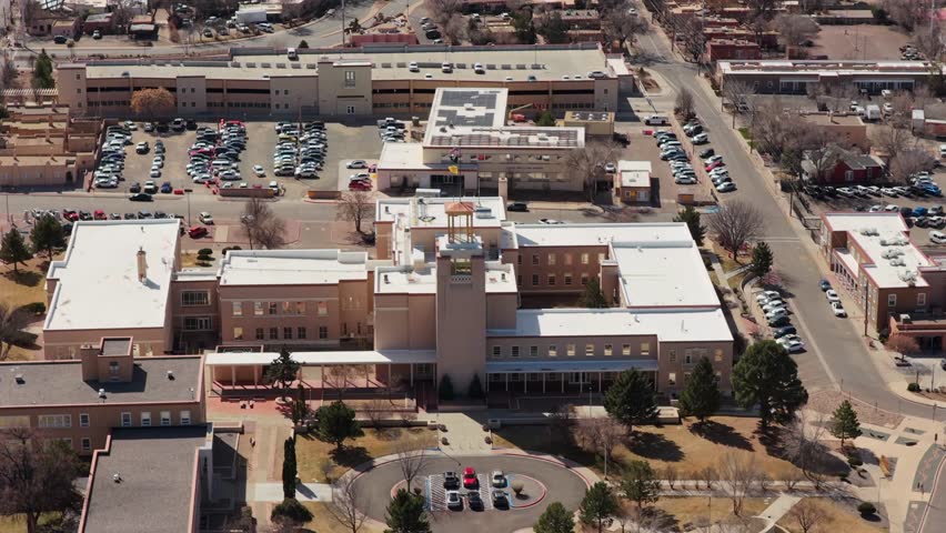 A smooth aerial retreat showcases the Zia-inspired design of the Roundhouse. The high-angle perspective captures the grand scale of the capitol grounds and the high-desert horizon.