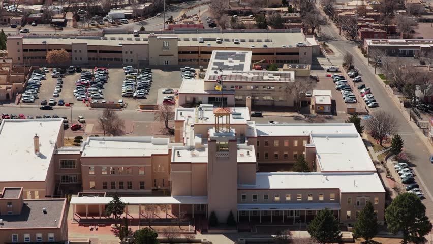 The camera reverses from the unique circular State Capitol to reveal the surrounding architecture of downtown Santa Fe. This 4K shot highlights the heart of New Mexico