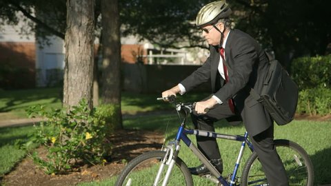 A businessman going green reduces his carbon footprint by riding a bike to work instead of driving the car.