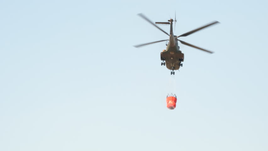 Aerial firefighting helicopter with bambi bucket flies off to fight wildfire