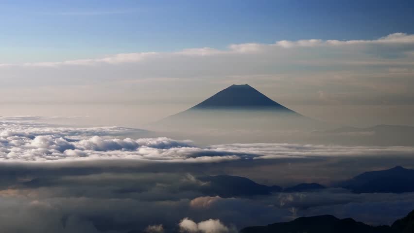 This video captures the 3,776-meter summit of Mount Fuji from a high-altitude vantage point. The visual documents the volcanic cone protruding through a dense sea of clouds during early morning light. The composition illustrates the terrestrial topography and atmospheric layers of the Southern Alps region, documenting Japanese geography in a high-resolution 4K format for environmental and travel media.