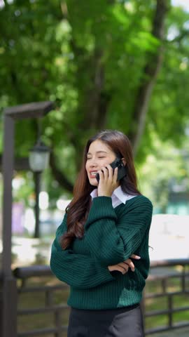Close-up of one university student playing with a smartphone outside a classroom building in a walkway.