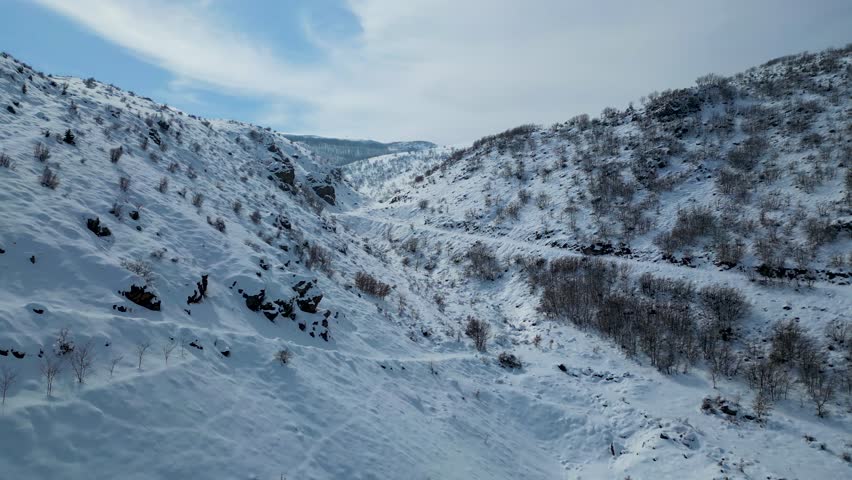 Aerial View of Winding Highway Through Snow-Covered Mountains
