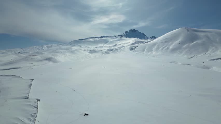 Aerial View of Winding Highway Through Snow-Covered Mountains