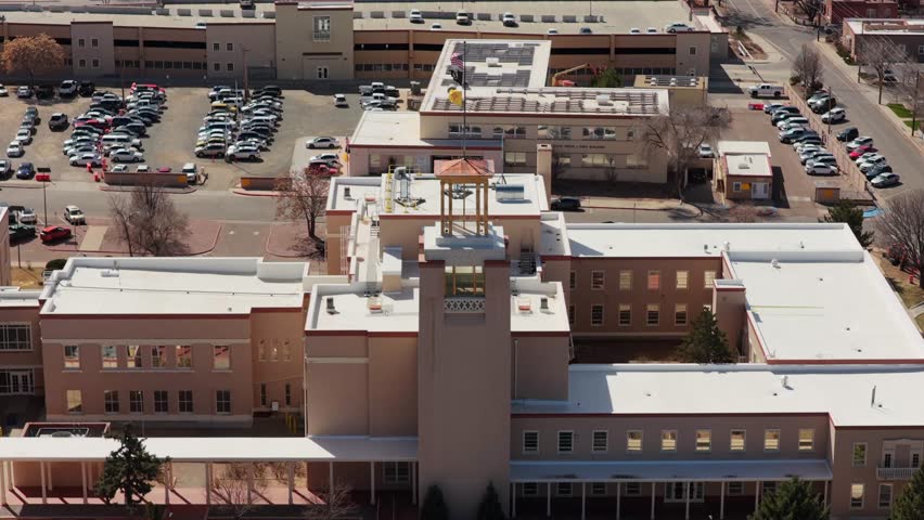 A high-angle drone perspective reveals the unique circular architecture of the New Mexico State Capitol. This 4K vista captures the heart of Santa Fe