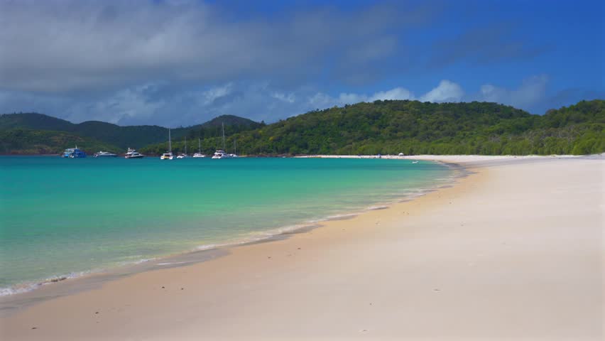 Whitehaven Beach Bay turquoise shallow shore calm water waves pristine white sandy beach sailboat yachts Whitsundays Australia morning sunny blue sky Great Barrier Reef Whitsunday Islands Coral Sea