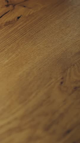 Vertical video. Close-up of a wooden floor. Wood texture close-up. Natural oak wooden floor, sanded and treated with natural transparent floor stain. High quality 4k footage