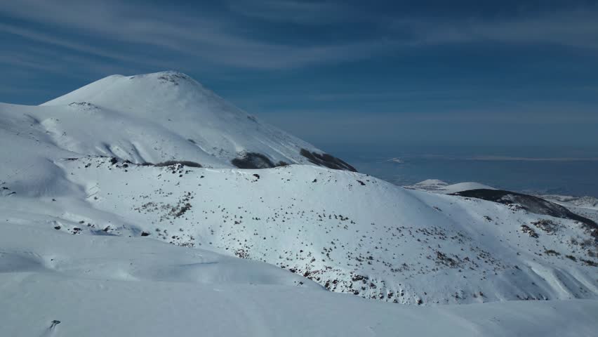 Aerial View of Winding Highway Through Snow-Covered Mountains