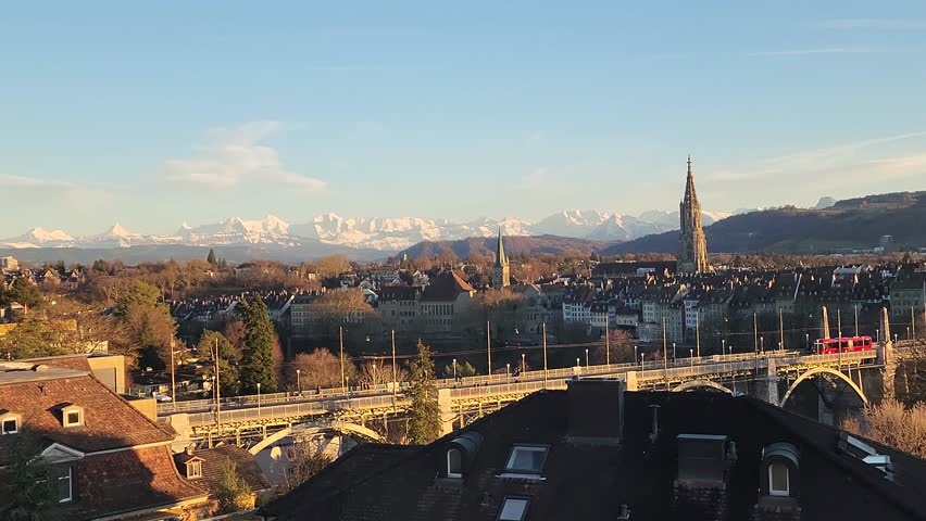 Bern capital city of Switzerland at sunset on a sunny winter day with the snow covered Alps in the background and golden light atmosphere. 