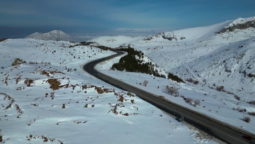 Aerial View of Winding Highway Through Snow-Covered Mountains