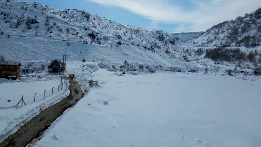 Aerial View of Winding Highway Through Snow-Covered Mountains