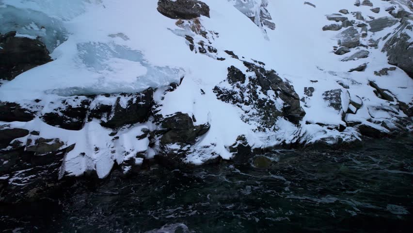 Wavy Arctic Sea water by icy cliffs by coast of Greenland, close slomo