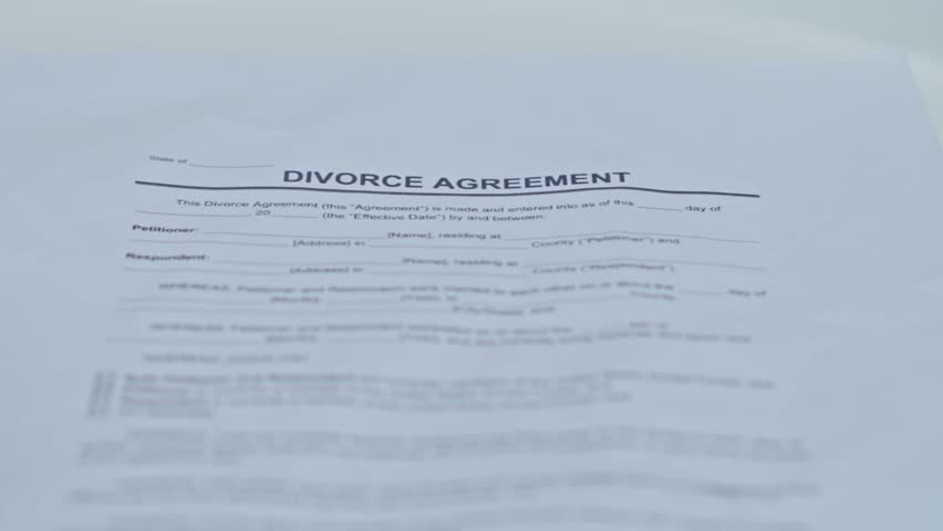 Two wedding rings being placed onto signed Divorce Agreement document
