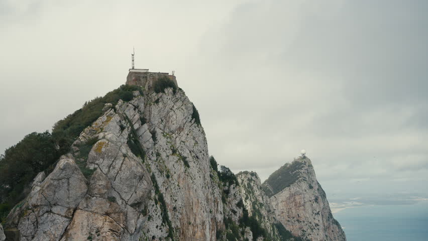 Steep limestone cliffs of the Rock of Gibraltar featuring O’Hara’s Battery and radar dome above the Mediterranean under overcast skies.