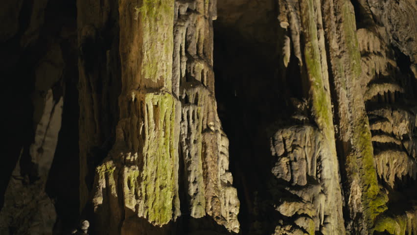 Detailed view of textured limestone columns and hanging stalactites inside St. Michael’s Cave, Gibraltar, lit with warm natural tones.