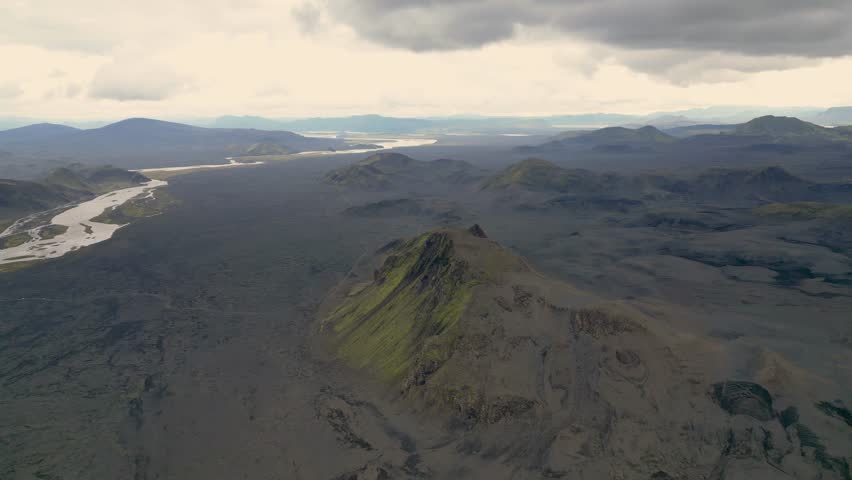 Aerial panoramic view of the colorful rhyolite mountains, volcanic landscape and lake in Landmannalaugar, Iceland. Dramatic highland scenery with green hills, lava fields and winding road in the Icelandic Highlands, popular destination for hiking and adventure travel.