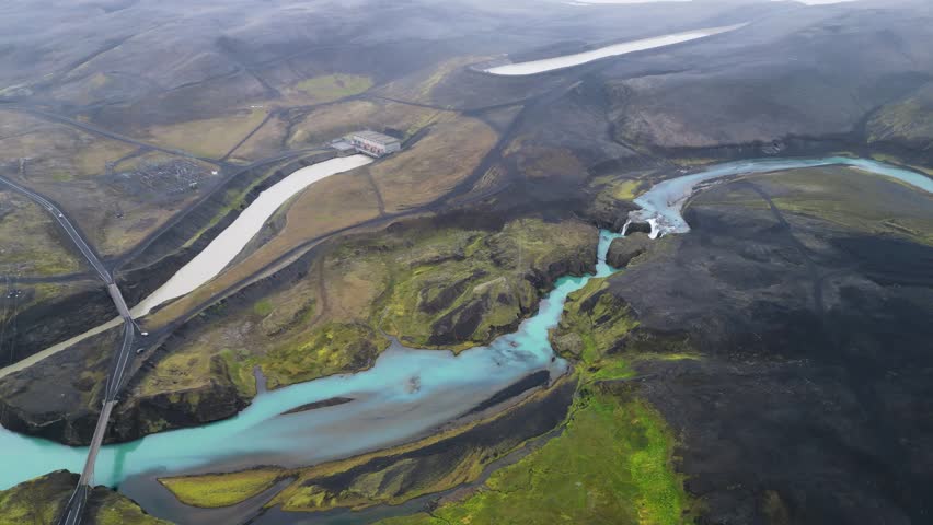 Aerial panoramic view of the colorful rhyolite mountains, volcanic landscape and lake in Landmannalaugar, Iceland. Dramatic highland scenery with green hills, lava fields and winding road in the Icelandic Highlands, popular destination for hiking and adventure travel.