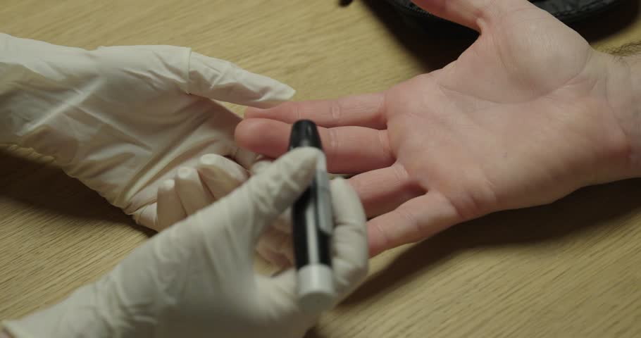 Close up of a blood glucose test showing a small drop of blood on a fingertip after lancet puncture, illustrating diabetes monitoring and medical testing procedure.