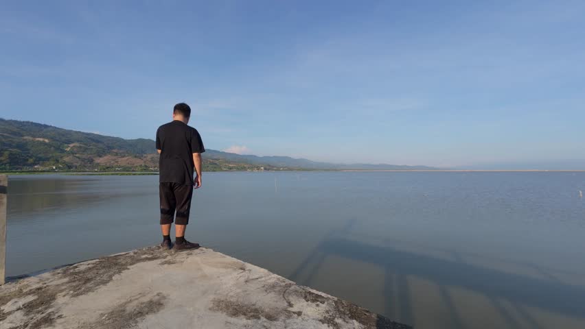 Man Gazing at Calm Lake and Mountains
