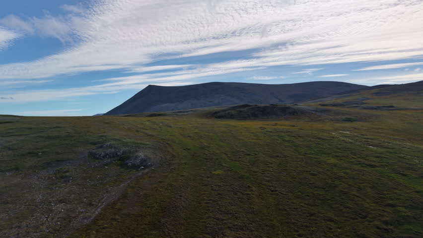 Aerial view of tundra plateau under a dark ridge and dramatic cloud near Lavrentiya Bay, Chukotka with summer color and soft light strong choice for travel opener, documentary scene and atmospheric st