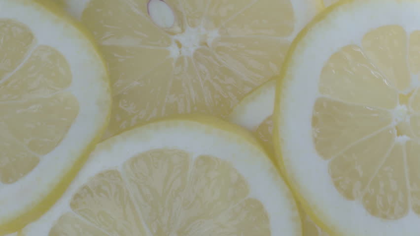 Extreme close-up of fresh lemon slices spinning. Detailed texture and bright yellow color create a dynamic and refreshing visual. Perfect for beverage, food, summer, and healthy lifestyle projects.