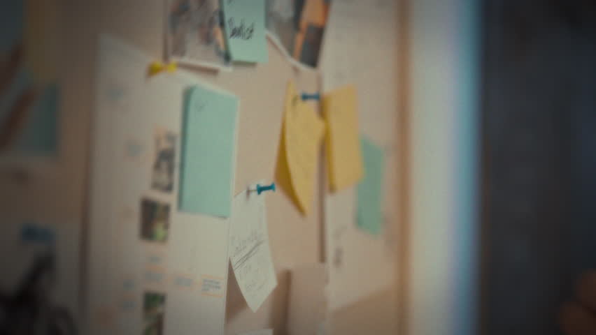 A mans hand meticulously organizes colorful, labeled sticky notes on a wall-mounted board, forming a visual representation of his goal-oriented plan, incorporating organization and reminder tools