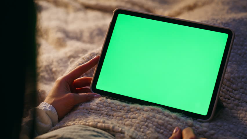 Unknown woman swiping mockup tablet display lying cozy home bed closeup. Lady hand touching green screen pad computer watching social media relaxing night bedroom. Freelancer working remote at evening