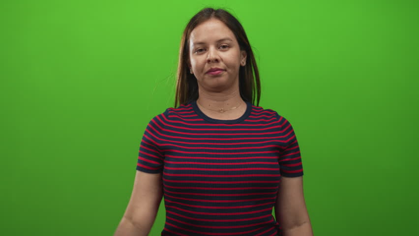 Young caucasian woman pinching fingers to indicate small size with neutral expression in green studio; dismissal smallness measurement.