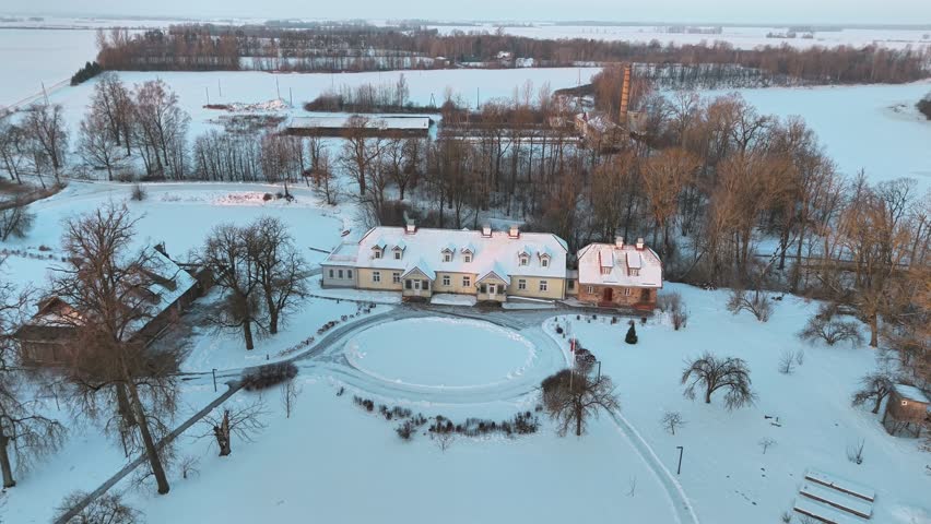 Large country house in Poland covered in snow, aerial flyover view to tilt down over rooftop