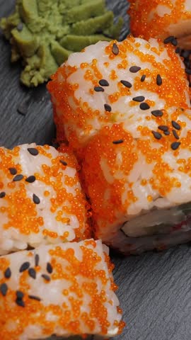 Sushi roll california on black slate plate. Rotate. Vertical footage