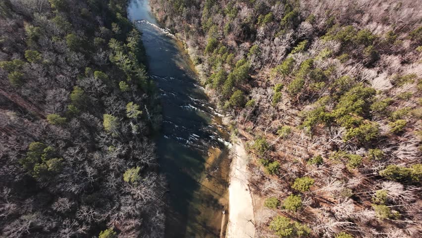 Cinematic aerial drone footage of the Upper Chattahoochee River winding through the forested landscape of North Georgia. Captured in natural light, the river curves between hardwood trees and rolling hills, creating a peaceful southern wilderness scene. Ideal for travel, tourism, environmental conservation, and nature background content.