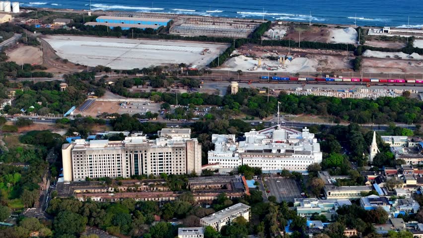 Aerial view of the Tamil Nadu Secretariat, Chennai, the grand white government complex near the Marina coastline. Railway lines and the Bay of Bengal form a dynamic urban and coastal backdrop.