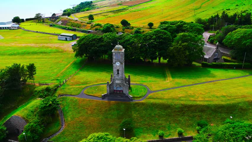 Cinematic drone orbit around the Helmsdale War Memorial Clock Tower in the Scottish Highlands showcasing historic architecture, coastal village setting and regional heritage landmark.