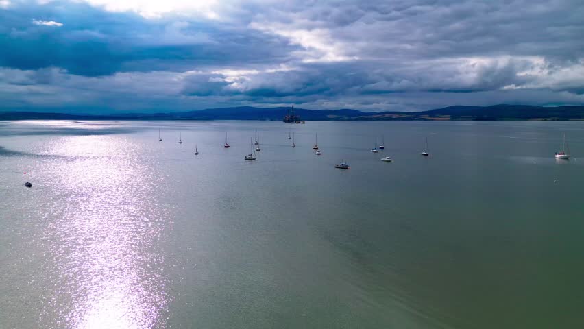 Drone footage of numerous boats anchored off the coast of Cromarty along the Cromarty Firth, showcasing a peaceful maritime setting and coastal lifestyle in the Scottish Highlands.