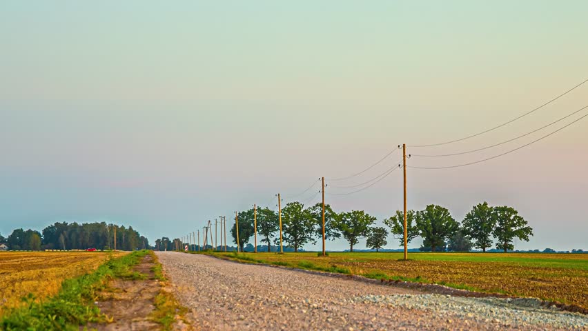 Low angle shot over a country road under a sunset in a bright blue sky.