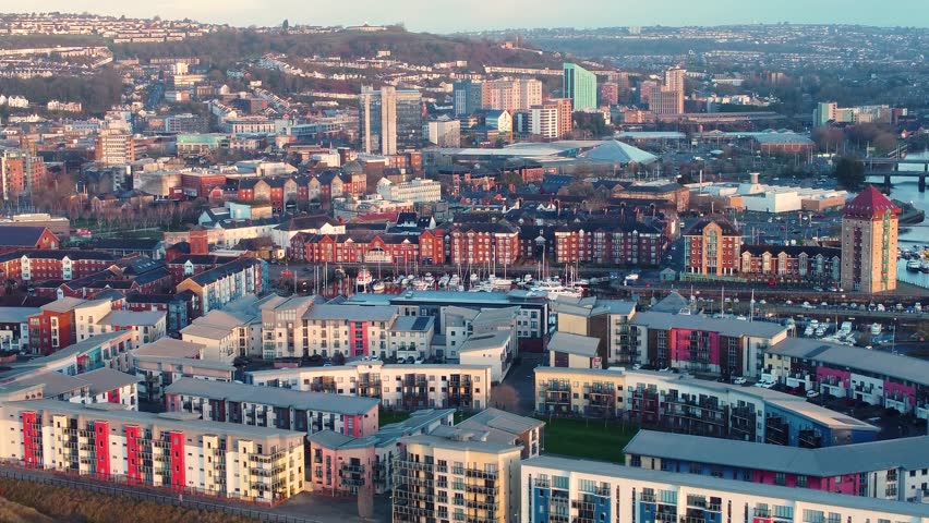 Aerial View Swansea City with various buildings at sunrise including luxury seaside real estate apartments and shopping centres with houses on hillside. Modern Urban Environment.