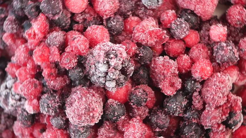 Macro close up of frozen mixed berries rotating on a table