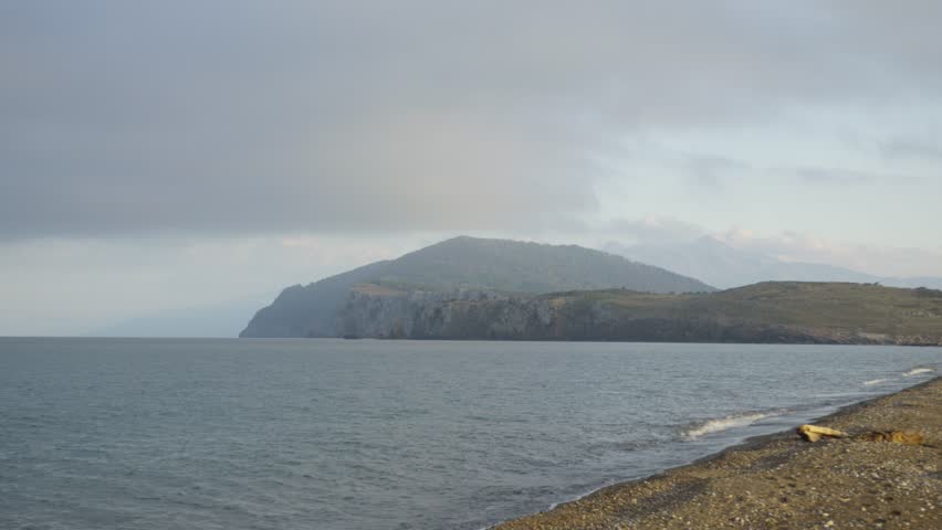 Peaceful coastal view at dawn with misty hills and gentle waves