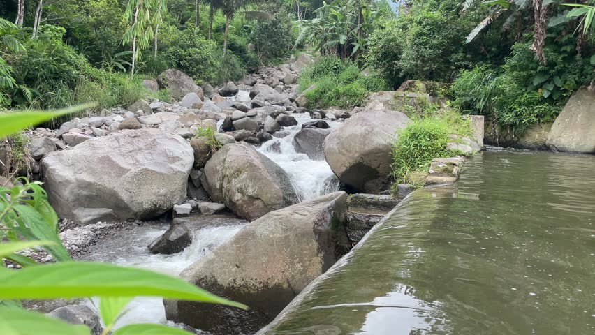 river with a mountain landscape view, featuring large rocks and trees