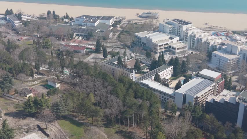 Drone aerial view of seaside city with hotels, buildings and beach creating modern coastal tourism landscape near sea.