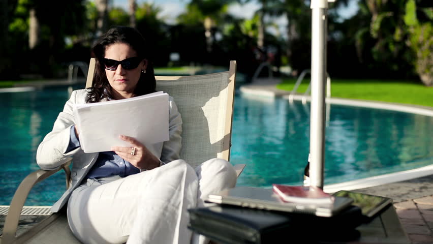 Businesswoman lying on sunbed and working with documents
