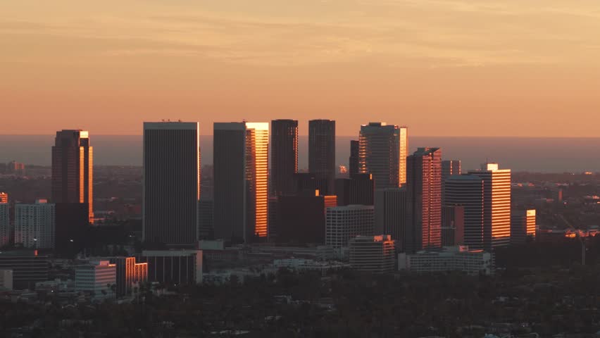 Telephoto panning aerial shot of Century City during golden hour in Los Angeles, California. 4K