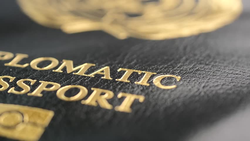 Close-up cinematic shot of diplomatic passport, featuring golden embossed text and official emblem, dynamic motion footage