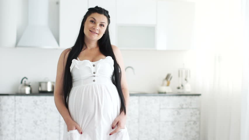 Beautiful pregnant woman stands and smiles
