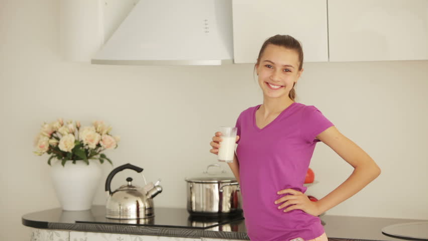 Girl standing in the kitchen with glass of milk
